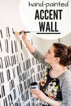 a woman painting a wall with black and white lines on it, the words hand painted accent wall above her