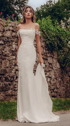 a woman in a white wedding dress standing on the street with her arms around her waist