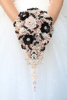 the bride's bouquet is made up of black and white flowers, pearls, and jewels