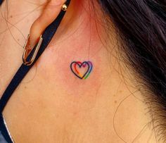 a colorful heart tattoo on the back of a woman's left ear and behind her ear