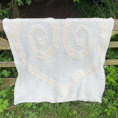 a white quilt with the word go written on it in cursive letters, sitting next to a wooden fence