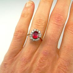 a woman's hand with a red and white diamond ring on top of it