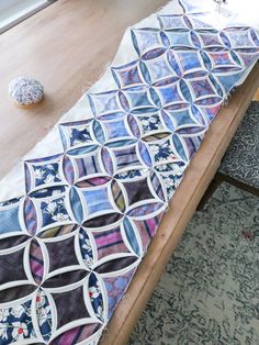 a wooden table topped with lots of different colored pieces of cloth on top of it