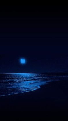 a full moon is seen over the ocean on a dark night with blue hues