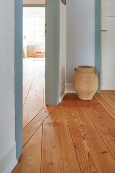 an empty room with a vase on the floor