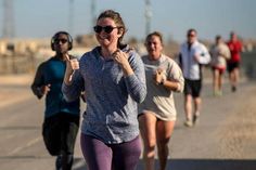 a group of people running down a road with one woman giving the thumbs up sign