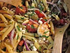 pasta salad with shrimp, olives, tomatoes and fettuccine in a wooden bowl