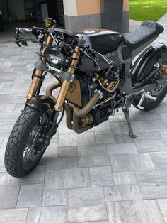 a black and gold motorcycle is parked on the sidewalk