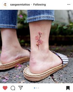 a woman's foot with a small pink flower tattoo on her left side ankle