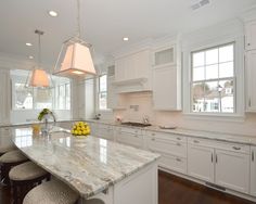 a large kitchen with white cabinets and marble counter tops