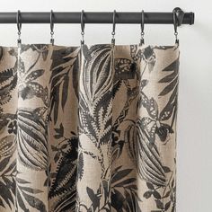 the curtains are hanging in front of the window with black and white leaves on them