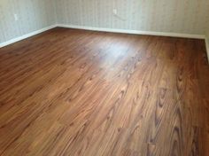 an empty room with hard wood flooring and white wallpaper on the other side