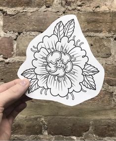 a hand holding up a sticker with an image of a flower in the middle