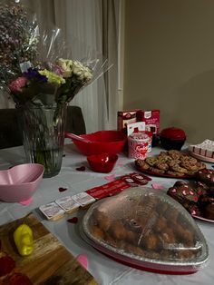 a table topped with lots of food and desserts next to a vase filled with flowers