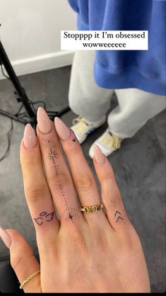 someone is holding their hand up to the camera with an arrow tattoo on her finger