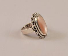 This stunning sterling silver dinner ring features an ornate setting and a gorgeous oblong mother of pearl stone that has just a hint of pink in it.  The stone is large and attention getting at 20 mm long and 10 mm wide.  The ring and the MOP are in excellent vintage condition and will make a wonderful gift for any number of occasions.  It is a Size 6 and marked .925 indicating that it is made from sterling quality silver.All of our jewelry pieces are sent with "tracking" in an attractive gift b Formal Oval Mother Of Pearl Rings, Elegant Pink Opal Ring In Sterling Silver, Elegant Pink Opal Sterling Silver Ring, Elegant Pink Opal Ring For Formal Occasions, Formal Pink Oval Opal Ring, Dinner Ring, Pearl Stone, Gold Choker, Moon Stone