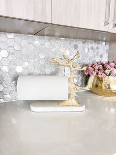 a white counter top with some gold vases on it and a toilet paper holder