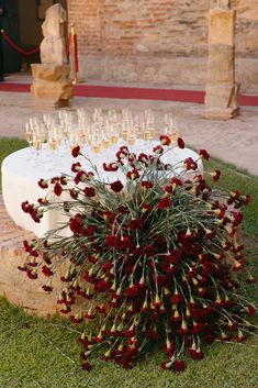 a bunch of wine glasses are sitting on a table with flowers in front of it