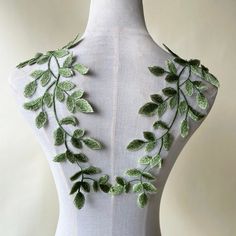 the back of a mannequin with green leaves on it's neckline