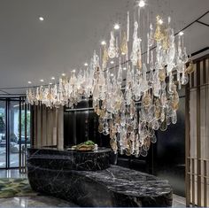 a large chandelier hanging from the ceiling in a room with marble counter tops