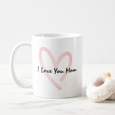 a white coffee mug with i love you mom written on it next to a donut