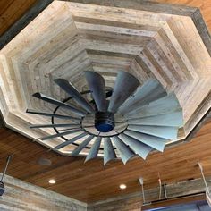 a ceiling fan in the middle of a room with wood paneling on the walls