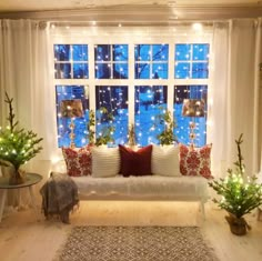 a living room filled with furniture and christmas trees in front of a window covered in lights