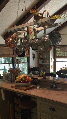 a kitchen filled with lots of pots and pans hanging from the ceiling next to a counter