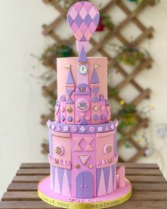 a pink and purple castle cake with a clock on it's top is sitting on a table