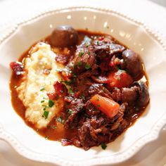 a white plate topped with meat and mashed potatoes