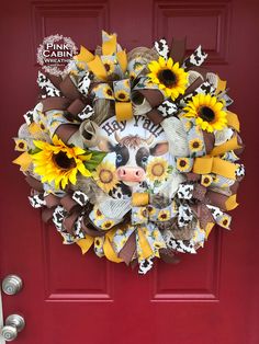 a wreath with sunflowers and cows is hanging on a red door that has the word farm written on it