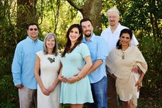 a group of people standing next to each other in front of some trees and bushes