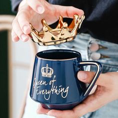 a person holding a coffee mug with a gold crown on it and the words queen of everything