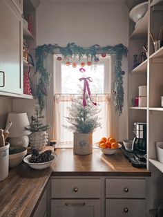 a kitchen with white cabinets and wooden counter tops covered in christmas decorations, including oranges