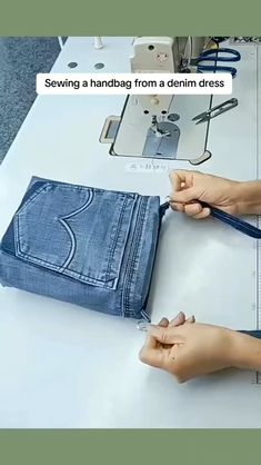 two hands are using scissors to sew a pair of blue jeans on a sewing machine