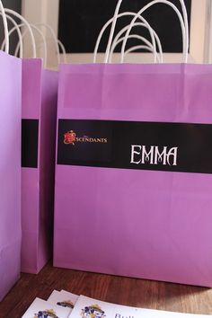 purple shopping bags sitting on top of a wooden table