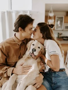 a man and woman kissing while holding a dog