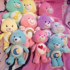 a pile of stuffed teddy bears sitting on top of a pink bed sheet with hearts and stars