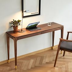 a laptop computer sitting on top of a wooden desk next to a chair and mirror