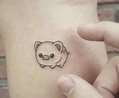 a small pig tattoo on the back of a woman's left arm and wrist