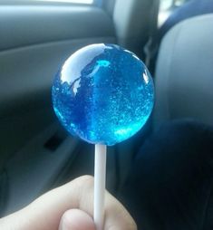 a person is holding a blue lollipop in their hand while sitting in the car