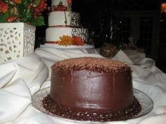 a chocolate cake sitting on top of a glass plate next to flowers and vases