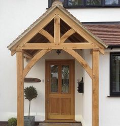 a house with a wooden front door and side entry way that has a planter next to it