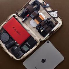 an apple laptop, camera and other electronics are sitting in a bag on the table