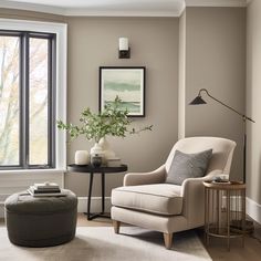 a living room with a chair, ottoman and coffee table in front of a window