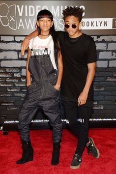 two young men standing next to each other on a red carpet