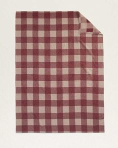 a red and white checkered blanket laying on top of a tablecloth with a folded end