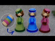 three knitted dolls sitting next to each other on the ground with yarn wrapped around them