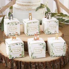 small boxes with animals on them sitting on a tree stump in front of a wedding cake