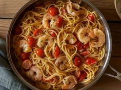 pasta with shrimp and tomatoes in a pan on a wooden table, ready to be eaten